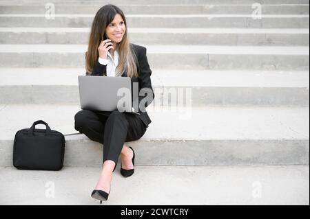 Jeune femme d'affaires utilisant un ordinateur portable dans la ville, assise sur un escalier. Photo de haute qualité Banque D'Images