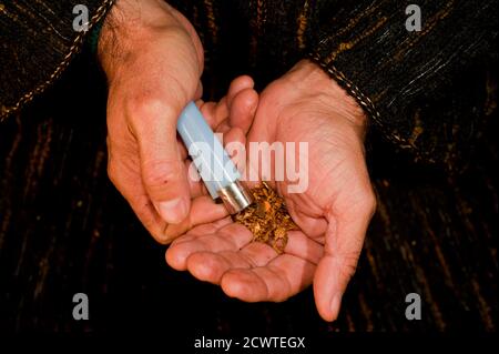 homme mains avec l'allume-cigare foncé grinçant allumé cigare dans la main chauffe morceau de haschisch, préparation de cigare haschisch Banque D'Images