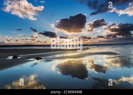 Le ciel au coucher du soleil se reflète dans les sables humides du plage ci-dessous Banque D'Images