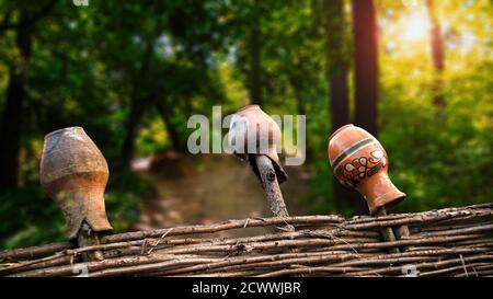 Cruches d'argile sur une clôture en osier avec une forêt verte en arrière-plan Banque D'Images