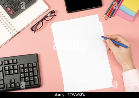 Vue de dessus de l'homme d'affaires travaillant avec les États financiers. Bureau rose moderne avec ordinateur portable, crayon et beaucoup de choses. Disposition de la table de pose à plat. S Banque D'Images