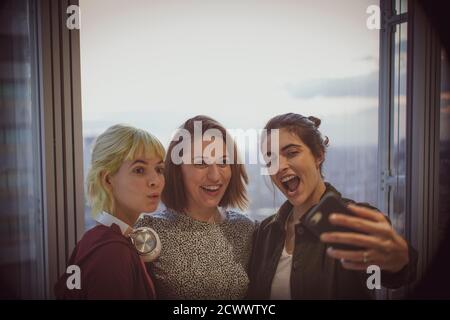 Des femmes d'affaires heureuses qui prennent le selfie à la fenêtre du bureau Banque D'Images
