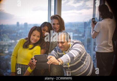 Les gens d'affaires prennent le selfie à la fenêtre du bureau en hauteur Banque D'Images
