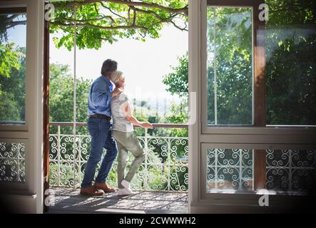 Couple senior affectueux se détendant sur un balcon ensoleillé Banque D'Images