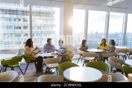 Les gens d'affaires mangent le déjeuner et parlent dans la cafétéria ensoleillée Banque D'Images