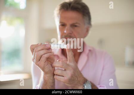Homme âgé souffrant de diabète utilisant un glucomètre sur le doigt Banque D'Images