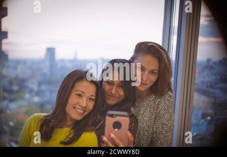 Femmes d'affaires emportant le selfie avec un smartphone à la fenêtre du bureau Banque D'Images
