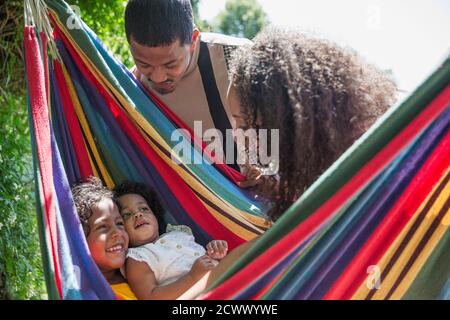Parents regardant des filles heureuses dans un hamac ensoleillé d'été Banque D'Images