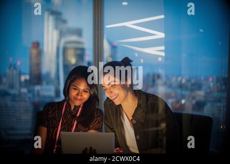 Femmes d'affaires avec tablette numérique travaillant tard dans le bureau, Londres, Royaume-Uni Banque D'Images