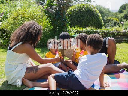 Bonne famille mangeant des pastèques de pastèque dans la cour ensoleillée d'été Banque D'Images