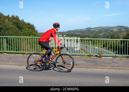 Cycliste mâle à cheval Boardman sports Road vélo sur la route de campagne traversant le pont d'autoroute dans la campagne du Lancashire, Royaume-Uni Banque D'Images