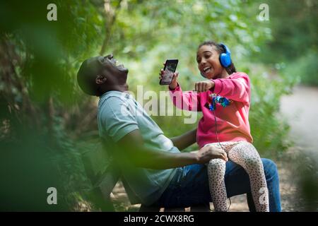 Père et fille heureux en train de rire sur le banc du parc Banque D'Images