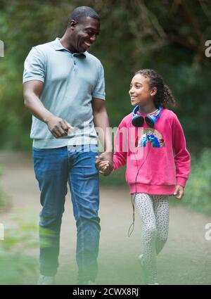 Père et fille heureux tenant les mains marchant sur le sentier du parc Banque D'Images