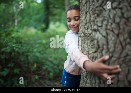 Jolie fille embrassant le tronc d'arbre dans les bois Banque D'Images