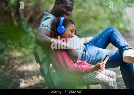 Père et fille avec casque et tablette numérique sur le parc banc Banque D'Images