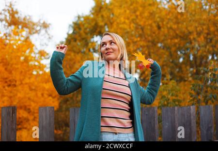 Bonne femme blonde en manteau bleu en profitant de la promenade dans le parc d'automne. Concept d'automne. Banque D'Images