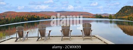 Fauteuils en bois sur la rive du lac Monroe et couleurs automnales dans le parc national du Mont-Tremblant, au Québec Banque D'Images