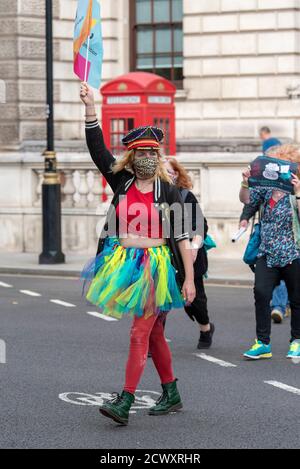 Une femme portant un masque de visage rejoint Pantomime dames lorsqu'elle marche à travers Londres. Pantomime dames a traversé Londres, tandis qu'ils se joignent à d'autres créatifs pour souligner la situation critique de l'industrie du théâtre et de ses travailleurs provoquée par la pandémie COVID-19. Banque D'Images