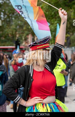 Une femme portant un masque de visage rejoint Pantomime dames lorsqu'elle marche à travers Londres. Pantomime dames a traversé Londres, tandis qu'ils se joignent à d'autres créatifs pour souligner la situation critique de l'industrie du théâtre et de ses travailleurs provoquée par la pandémie COVID-19. Banque D'Images