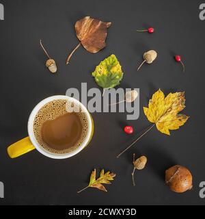 Vue de dessus d'une tasse de café entourée par l'automne feuilles et glands sur une surface grise Banque D'Images