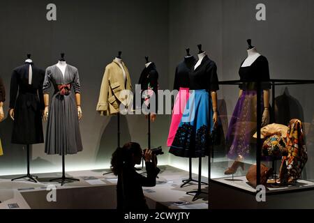 A visitor takes picture of vintage dresses by designers Jacques Fath,  Pauline Trigere, Gres, Pierre Balmain, Givenchy and Schiaparelli presented  in the exhibition 