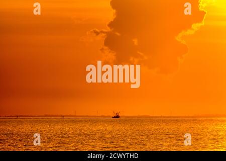 Un bateau de pêche dans la Lash a silhoueté contre un beau coucher de soleil orange. Banque D'Images