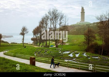 A Coruna, Galice, Espagne - 10 février 2020 : UN homme marche son chien dans un parc public sous la Tour d'Hercule, ancien phare romain. Intégré à la Banque D'Images