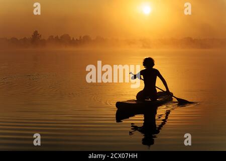 Homme dans la silhouette en utilisant la palette pour flotter sur le panneau sup Banque D'Images