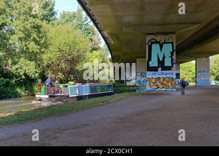 Un bateau étroit qui passe sous l'autoroute M25 Le canal de navigation de la rivière Wey à New Haw Surrey, en Angleterre ROYAUME-UNI Banque D'Images