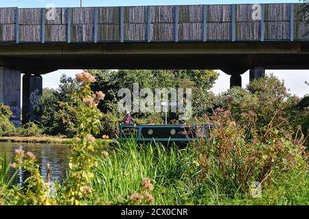 Un bateau étroit qui passe sous l'autoroute M25 Le canal de navigation de la rivière Wey à New Haw Surrey, en Angleterre ROYAUME-UNI Banque D'Images