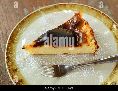 Tranche de cheesecake basque maison brûlé sur une table rustique en bois Banque D'Images