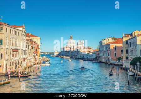 Paysage urbain de Venise avec voie navigable du Grand Canal. Gondoles et bateaux amarrés et bateau à voile Canal Grande. Église catholique romaine Santa Maria della Salute à Punta della Dogana. Vénétie, Italie. Banque D'Images