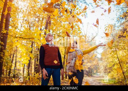 Saison d'automne. Un couple familial jette des feuilles dans la forêt d'automne. Les personnes âgées s'amusent en plein air en profitant de jeux de nature Banque D'Images
