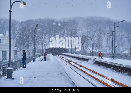 Kiev, UKRAINE - le 4 mars 2018 : la station de métro Dnipro plate-forme avec passagers train en attente et les travailleurs de la neige durant le nettoyage de neige, Kiev, Ukraine Banque D'Images