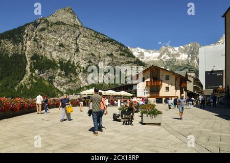 Piazza Abbé Henry, la place principale de la célèbre ville alpine, avec des touristes et des routards, le massif du Mont Chetif et du Mont blanc en été, Courmayeur Banque D'Images