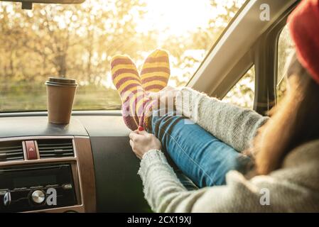 Femme en voiture dans des chaussettes chaudes jaune laine sur le tableau de bord de la voiture. Confortable week-end d'automne. Le concept de la liberté de voyager Banque D'Images