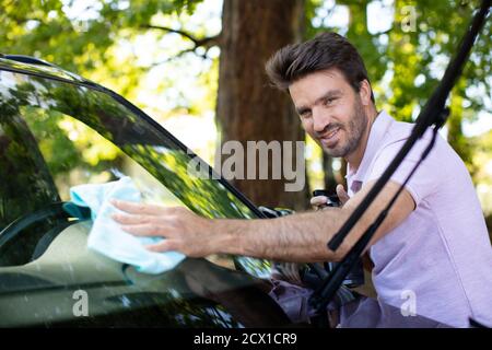 le personnel du service automobile nettoie le pare-brise arrière de la voiture avec un chiffon en microfibre Banque D'Images
