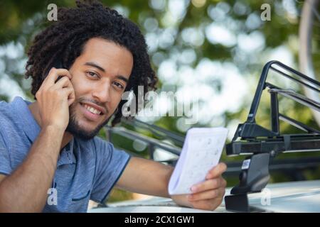 homme souriant utilisant un smartphone lors de l'installation d'un toit de voiture Banque D'Images