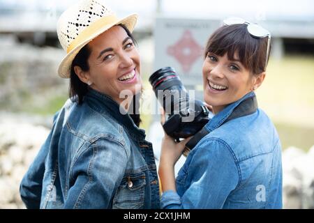 deux femmes en vacances tiennent un appareil photo avec objectif zoom Banque D'Images