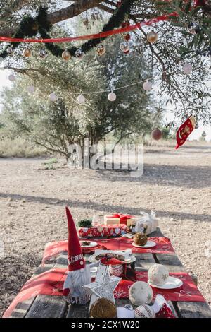 Décorations de Noël sur une table de pique-nique sous un olivier décoré, à la campagne après une collation familiale Banque D'Images