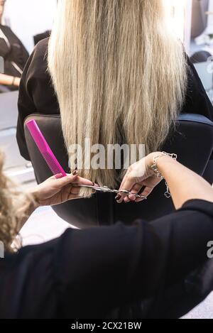 Gros plan d'un coiffeur coupant les cheveux d'une femme dans un salon de beauté Banque D'Images