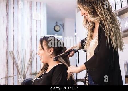 Femme cheveux curling coiffeur en salon de coiffure client Banque D'Images