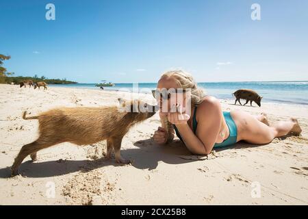 Jeune femme embrassant le porcelet en étant allongé sur le sable à la plage pendant les vacances d'été Banque D'Images