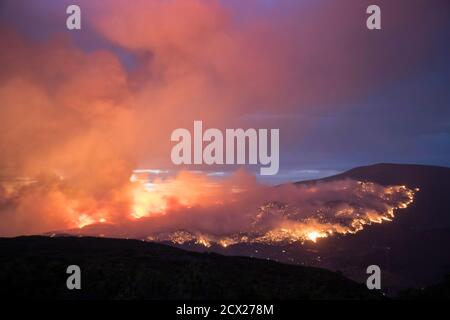 Fumée émise par un feu de forêt sur la montagne contre le ciel au crépuscule Banque D'Images