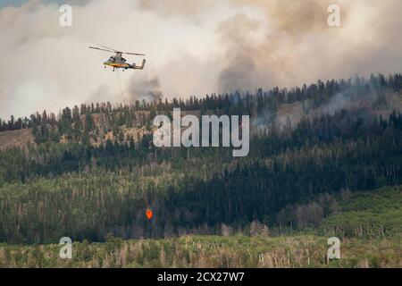 Hélicoptère militaire volant avec un produit ignifuge alors qu'il émet de la fumée forêt Banque D'Images