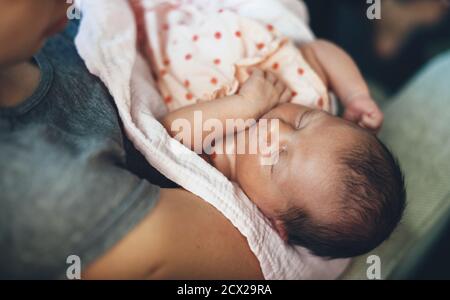 Vue de dessus photo d'un bébé caucasien dormant et rêvant dans ses mains de mères portant une jolie robe rose Banque D'Images