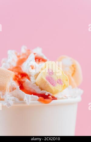 glace dans un verre avec caramel et guimauves un fond rose Banque D'Images