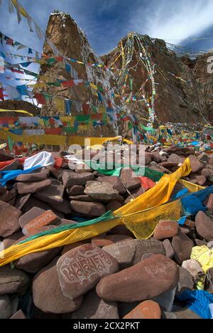 Pierres sculptées avec des écrits bouddhistes dans des textes tibétains et des payerflags à un endroit criard à côté du lac Nam TSO, Tibet Banque D'Images