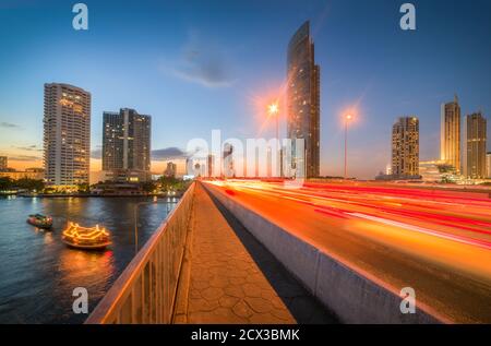 Gratte-ciels et feux de circulation sur le pont Taksin traversant la rivière Chao Phraya à Bangkok, Thaïlande au crépuscule Banque D'Images