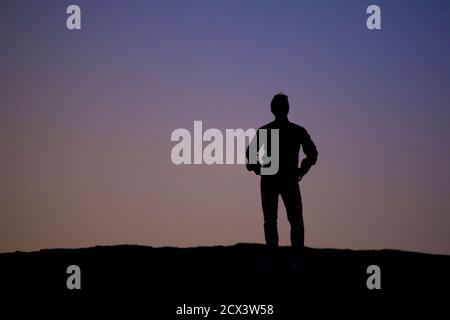 Figure solitaire silhouetée contre le ciel de la région de Kaluts du désert de LUT. L'endroit le plus chaud sur terre. Iran. Modèle validé Banque D'Images